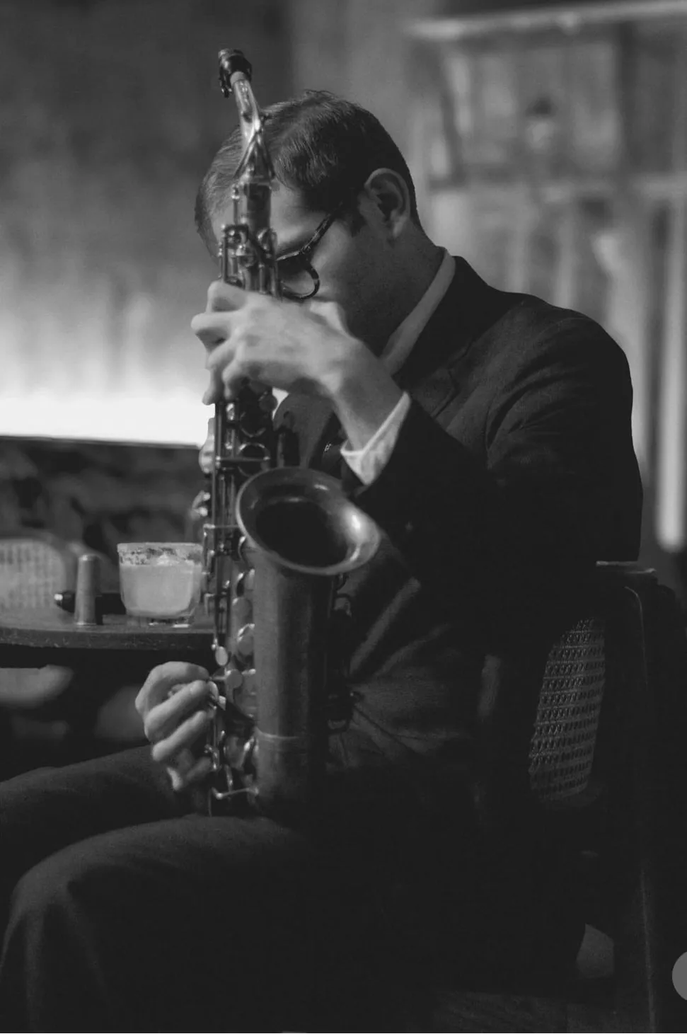 Aaron Johnson leaning into a phrase on alto saxophone at a club, in black and white.