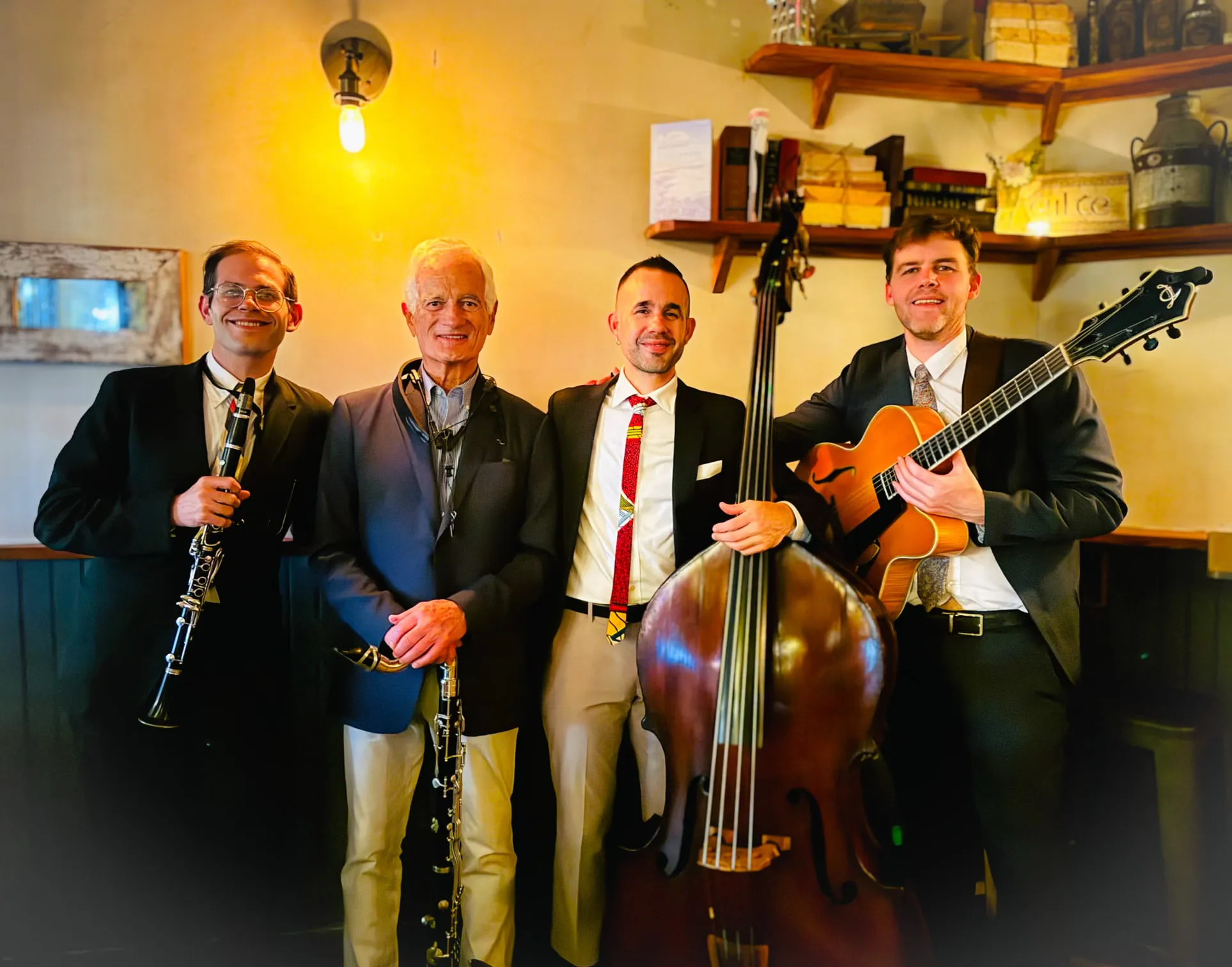Aaron Johnson holding a clarinet beside three fellow musicians with a bass clarinet, double bass and archtop guitar.