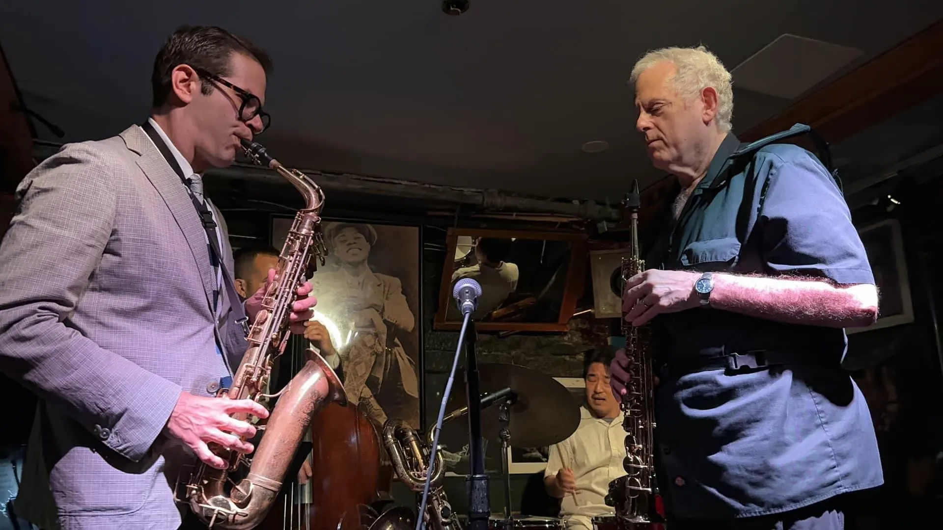 Aaron Johnson trading phrases with a second saxophonist on a club bandstand.